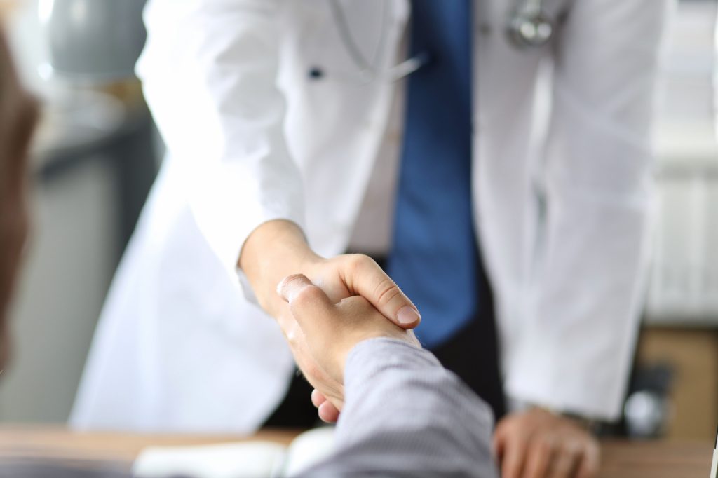 Médecin serrant la main d'un patient